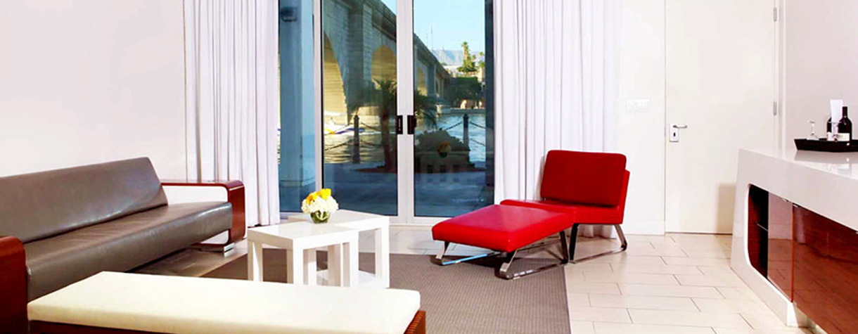 Heat Hotel guest room with beige leather sofa and lounging red leather chair